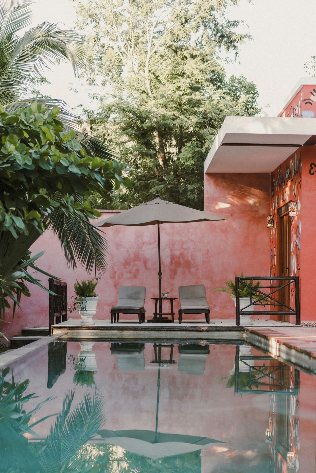 Courtyard pool beside a pink wall with two loungers