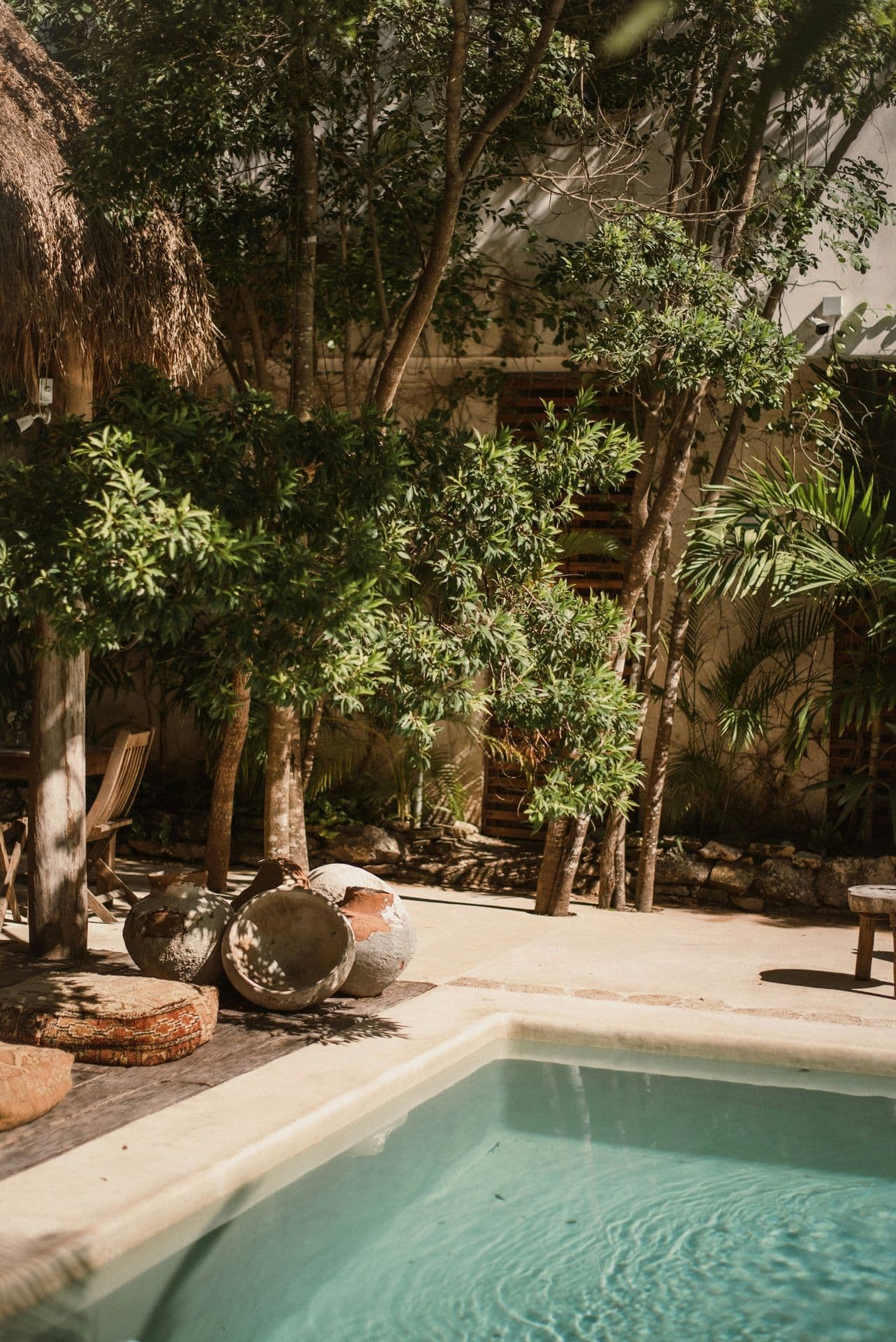 Shaded courtyard pool with clay pots and trees