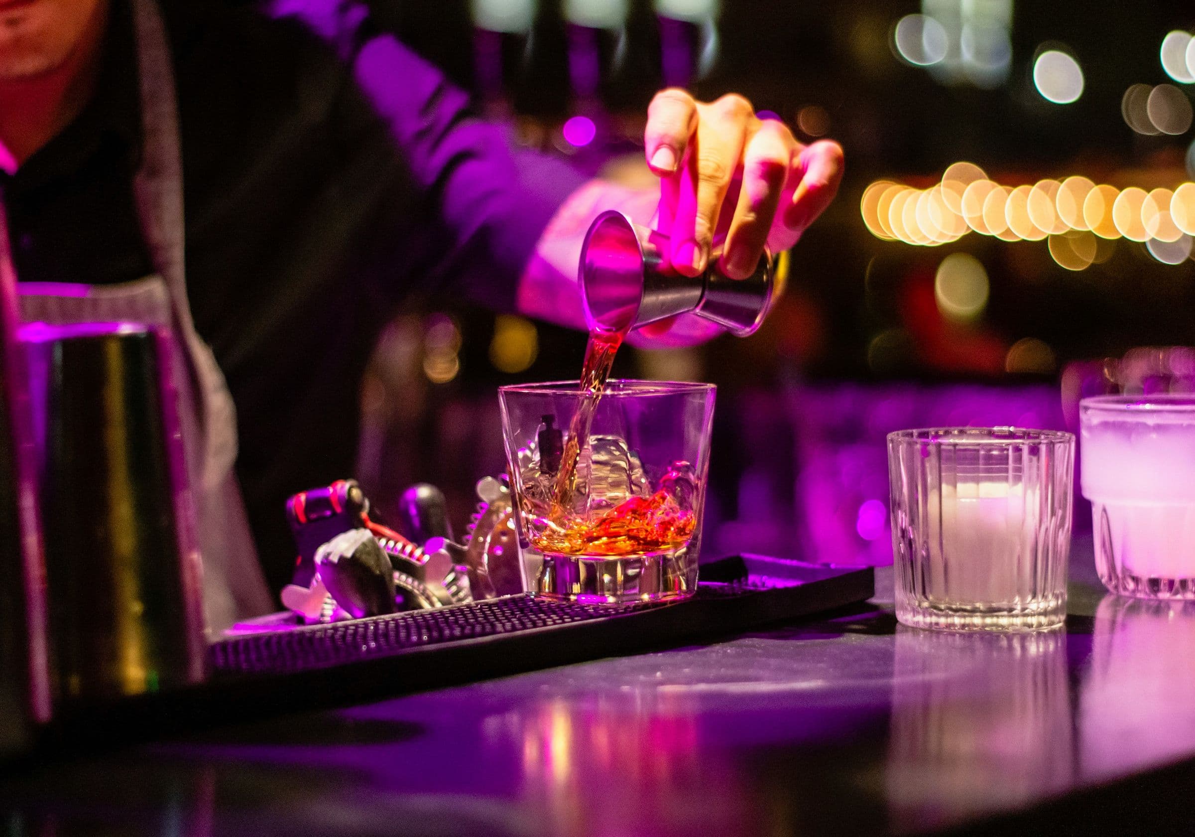 Bartender pouring a drink under purple light