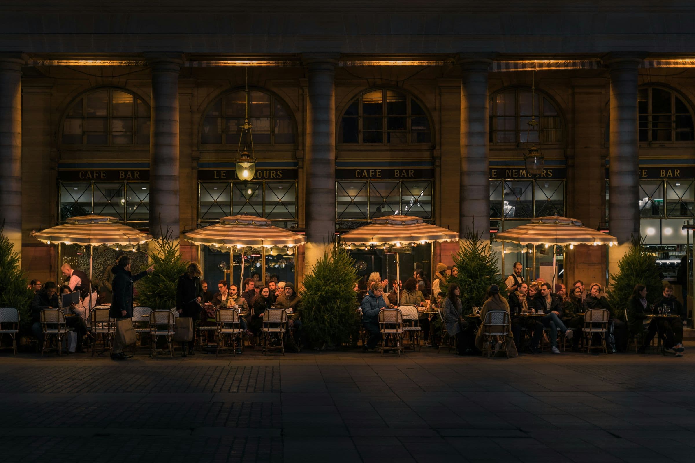Café terrace at night under a colonnade
