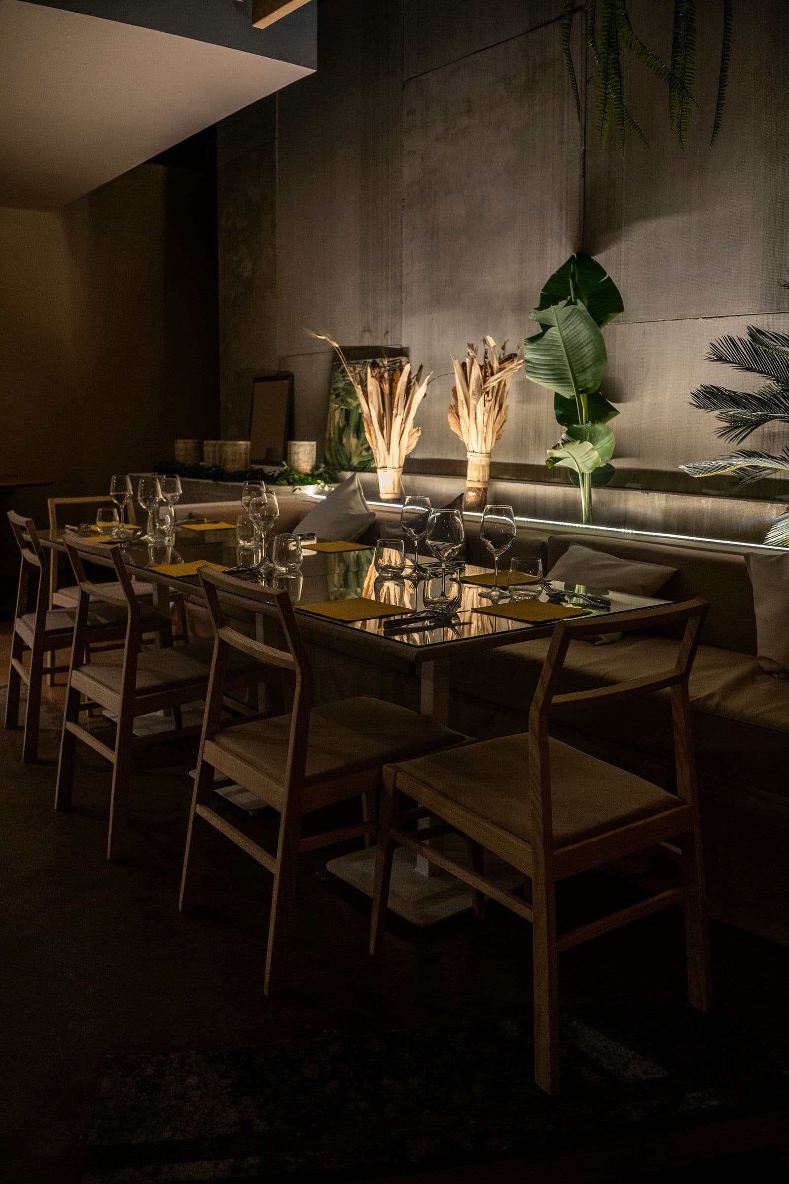 Restaurant tables set for dinner beside a planted wall