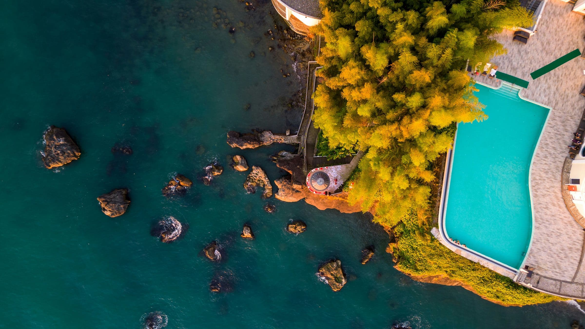 Aerial view of a clifftop resort pool above the sea