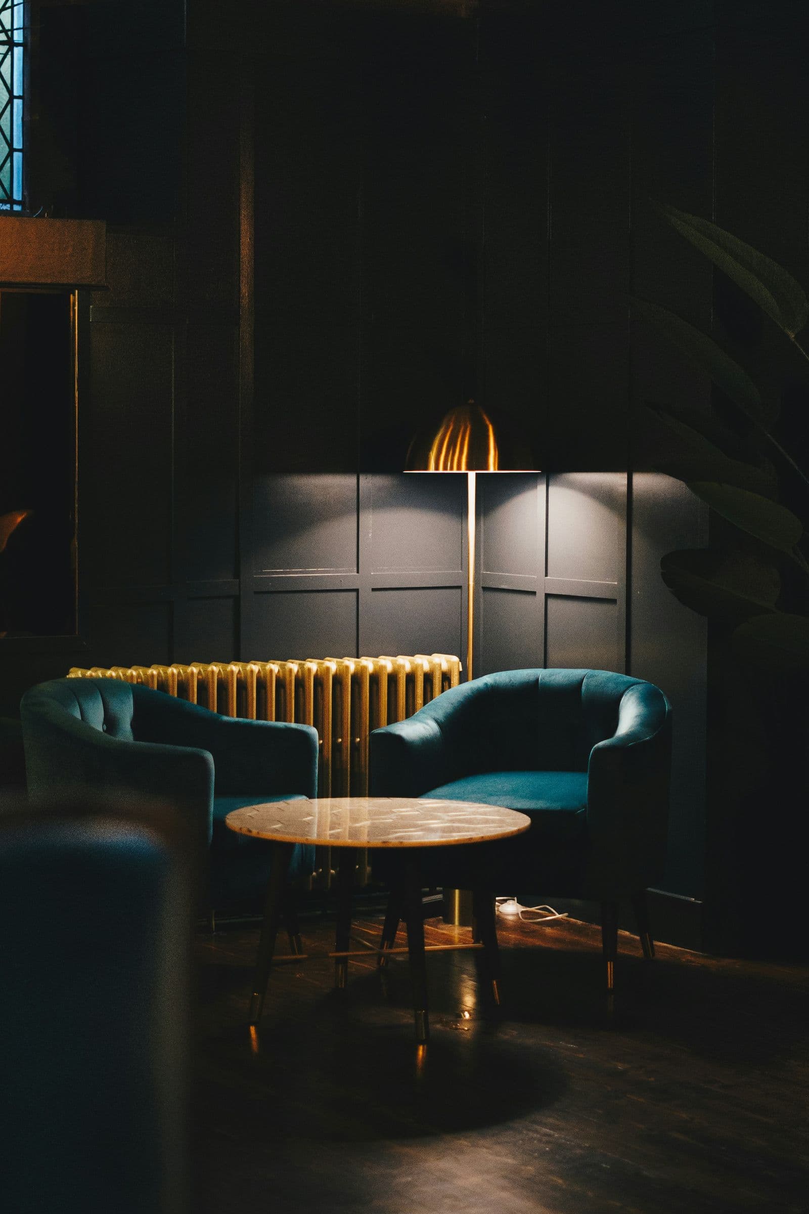 Teal armchairs in a dark-panelled lounge